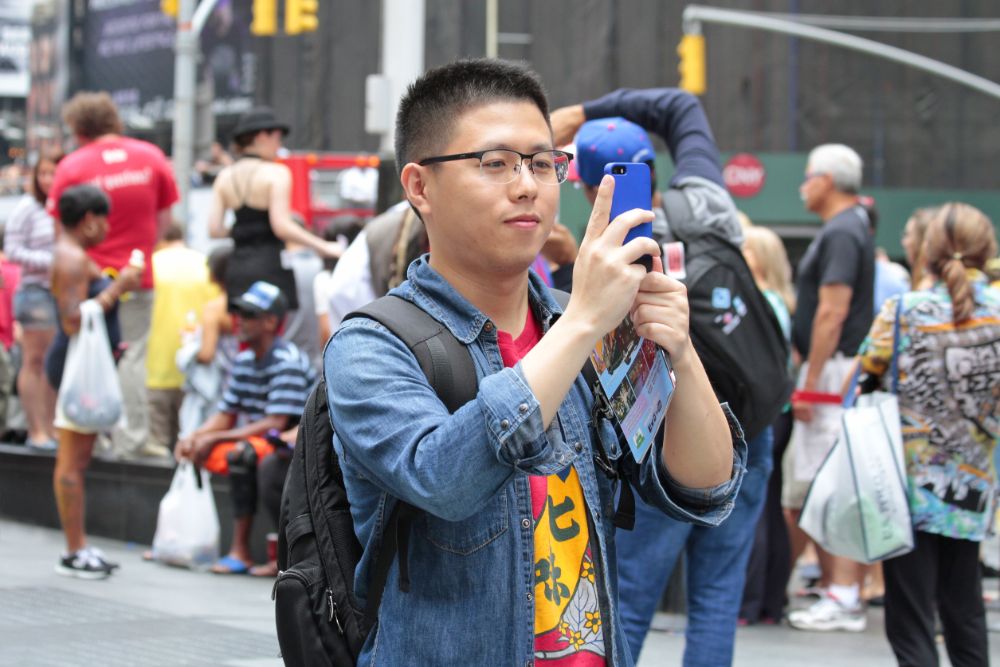 Chinese young tourist visiting New York City taking pictures of sights