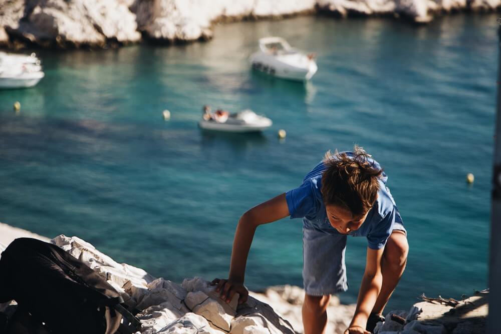 Small child climbing the rocks in the Mediterranean sea