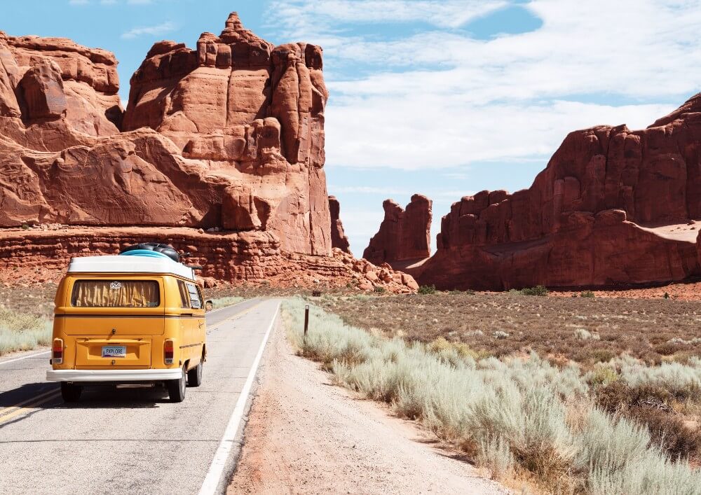 Yellow bus on a highway in the desert, investing and traveling the world
