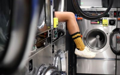 Girl sitting inside washing machine at dry cleaners during trip